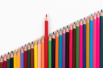 Fototapeta premium One pencil standing out from the group of other pencil on white background