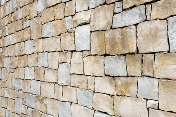 Light warm yellow sandstone wall made of square blocks seen in perspective.