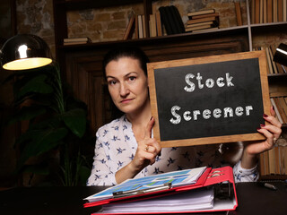 Young woman holding a black chalkboard in hands. Conceptual photo about Stock Screener with written...