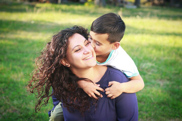 Happy smiling mixed race mother and son spending time outdoors Cute child hugging and kissing mother