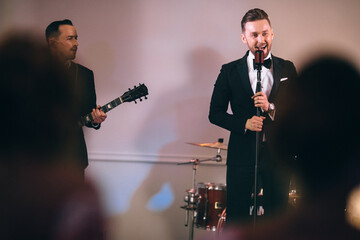 man in a suit singing on stage