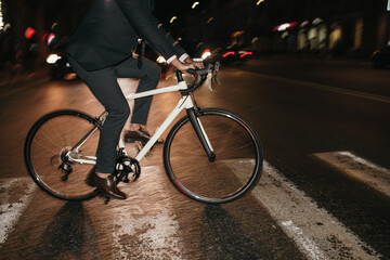 Stylish cyclist crossing road in night city