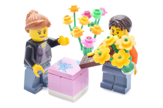 Loerrach, BW  Germany - February, 02th 2021: Lego minifigures couple in love with flowers, present box and chocolate. Editorial illustrative image of valentines day holiday. Studio shot. 
