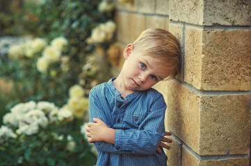 Portrait of a pensive little boy in a blue shirt on the street . Image of children . - 410341449