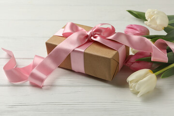 Beautiful tulips and gift box on white wooden background