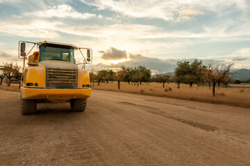 Fototapeta na wymiar A dump truck parked on a construction site at sunset in a lonely field