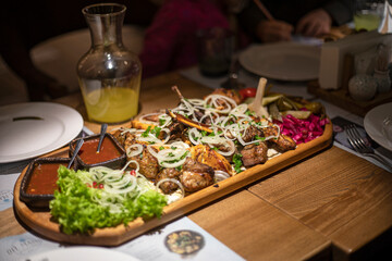 set of mixed meat with salad and sauce on a board with lemonade for a company on a table, horizontal