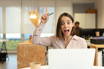 Inspired hispanic woman having an idea while looking her laptop in the office.