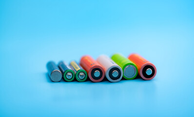 Rechargeable battery on blue background. Positive and negative terminals of rechargeable...