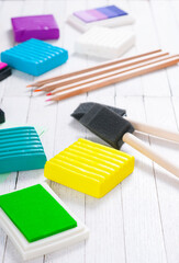 pencils, painting brushes, plasticine blocks and ink pads on white wood