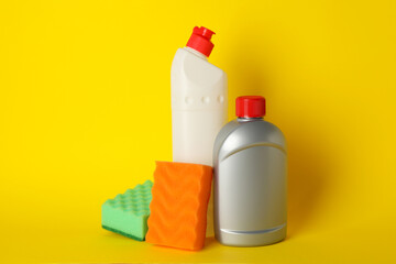 Detergents and sponges on yellow background, space for text