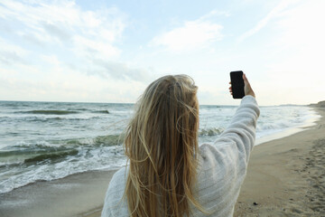 Young woman making selfie on sandy sea beach