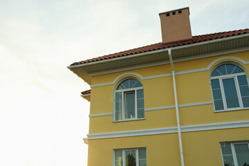 Fototapeta na wymiar Beautiful new yellow townhouse against sky with sunlight