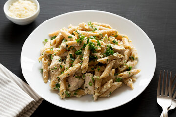 Homemade Chicken Alfredo Penne with Parsley on a black background, side view.