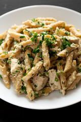 Homemade Chicken Alfredo Penne with Parsley on a black surface, low angle view. Close-up.