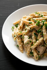 Homemade Chicken Alfredo Penne with Parsley on a black background, low angle view. Close-up.