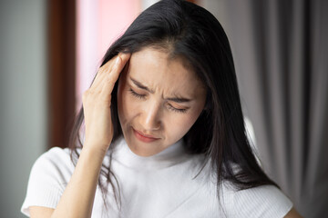 Fototapeta premium portrait of stressed sick asian woman with headache, depressed woman suffers from vertigo, dizziness, migraine, hangover, overwork, office syndrome depicting health care and mental health concept