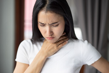 Fototapeta na wymiar Sick asian woman having sore throat and staying home indoor, concept of coronavirus symptomatic infection, lockdown, social distancing, new normal lifestyle of pre coronavirus cure, COVID-19 vaccine