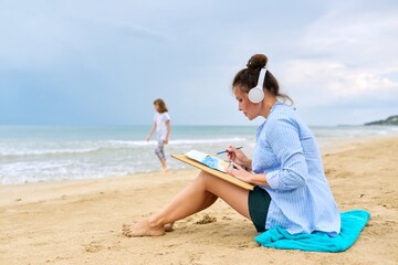 Mature woman with headphones listening to music enjoying watercolor painting