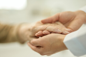 Caring doctor holding and examining hand of a senior patient