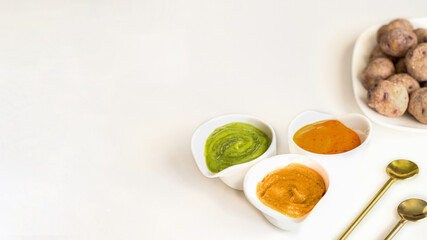 Canary Islands popular dish Papas Arrugadas (wrinkly potatoes) with Mojo picon (Red hot sauce),  Mojo verde (Green sauce) and Almogrote (cheese sauce) on table at restaurant