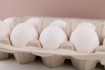 fresh raw chicken eggs in a cardboard tray on a white background