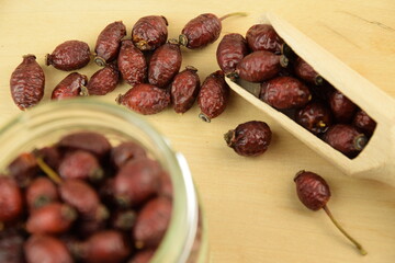 Rose hips, dried wild rose fruits on jar, natural wooden background, super food, healthy fruits, vitamin C and antioxidants resource