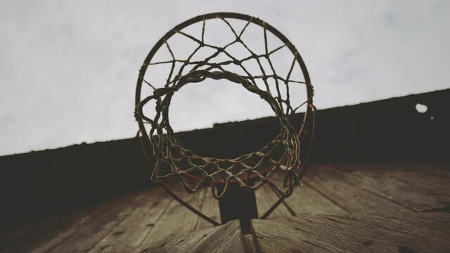 Basketball hoop with a net on the wall of a wooden barn outside the city. Against the background of the sky in the clouds in autumn.