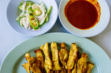 grilled pork satay with peanut sauce and vinegar on table