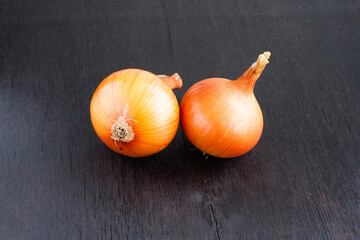 unpeeled ripe onions on a dark wooden background