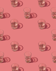 Gin and tonic crystal glasses garnished with rose buds and red peppercorns on a pastel pink background. Creative summer cocktail pattern.