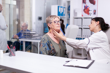 Obraz premium Professional physician checking neck lymph nodes of old woman, palpating senior woman. Elderly patient visiting doctor at hospital examining thyroid throat touching health at clinic, treatment medical