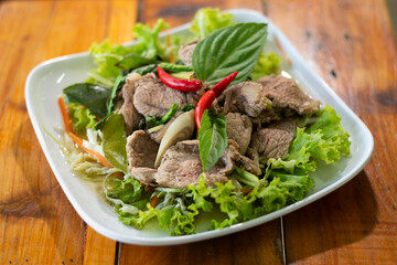 A dish of steamed beef served with vegetable isolated on wooden background.