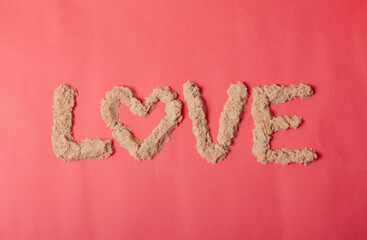 word love made from kinetic sand on pink background