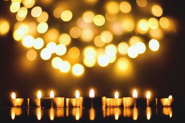 Burning candles with festive bokeh on a black background. Holiday concept. The concept of prayer and hope.