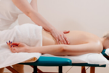 Back massage. The masseuse massages the woman's back. Hand movements of the masseur.