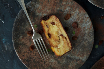 Bakery panettone pudding cake with raisins and chocolate on dark background. Top view with copy space.