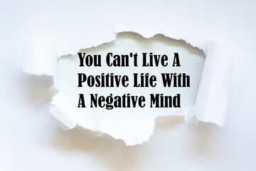 You Can't Live A Positive Life With A Negative Mind. Words written under torn paper. Motivation...