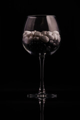 Glass on a thin leg with decorative stones on a black background.