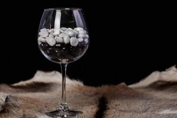 Beautiful glass goblet with black and white stones on a black background.
