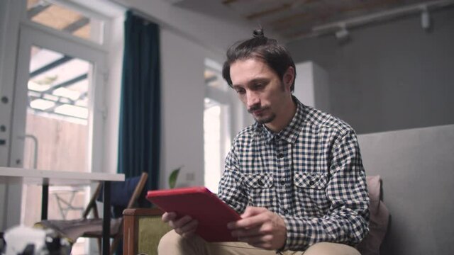 Guy sitting reads information from tablet