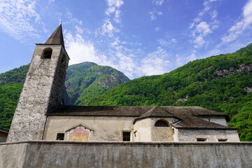 Medieval church in Ticino, Switzerland, with a vegetated mountain in background