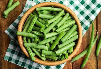 Fresh green beans in bowl on wooden table, flat lay
