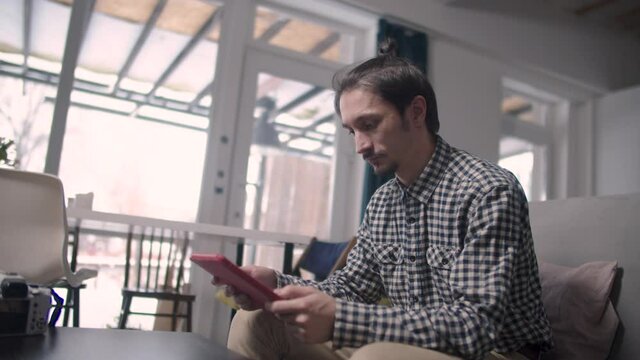 Guy sitting reads information from tablet