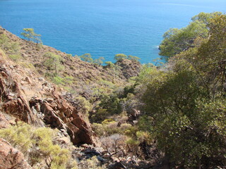 Fototapeta na wymiar Dizzying view from the incredible height of a steep cliff on the rocky coast of the azure sea bay.