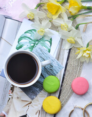 Top shot of a table with a cup of coffee and a bouquet of spring flowers on a white table top. coffee, magazines and cake. Top view flat style. Close up, copy space