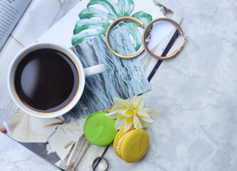 Top shot of a table with a cup of coffee and a bouquet of spring flowers on a white table top. coffee, magazines and cake. Top view flat style. Close up, copy space