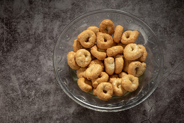 Tarallini in a glass bowl, on a gray mottled background