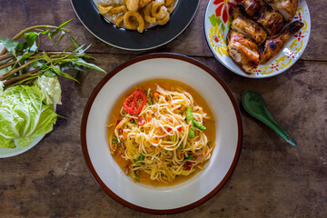 green papaya salad in black plate on wooden background