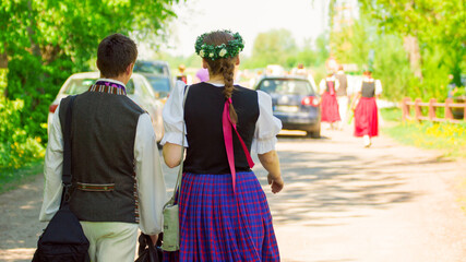 Two Latvian dancers in national costume going to concert. - obrazy, fototapety, plakaty
